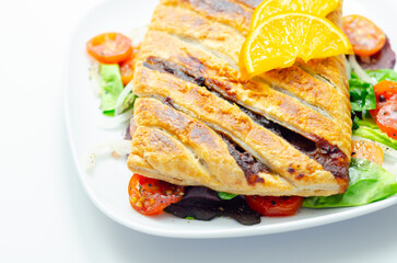 A plate of food with a pastry and a slice of orange on top
