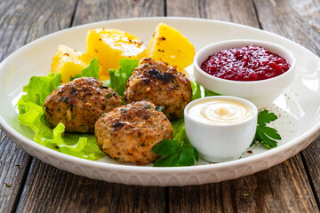 Baked meatballs, boiled potatoes, beetroots, fresh vegetables and mayonnaise served on white plate on wooden table
