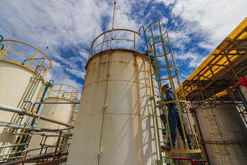 Male worker climbs up the ladder inspection stainless tank work at height
