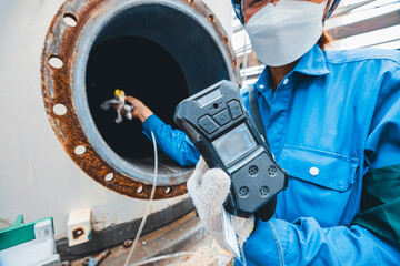 Worker female hand holding gas detector inspection safety gas testing at front manhole tank chemical