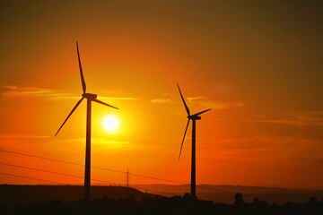 Fototapeta premium Siluetas de molinos de viento con el Sol al atardecer. Energías renovables 