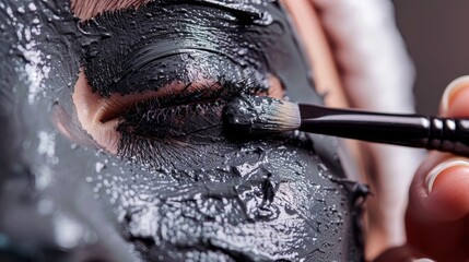 Close-up of applying charcoal mask on nose skin, showcasing texture and detoxifying properties