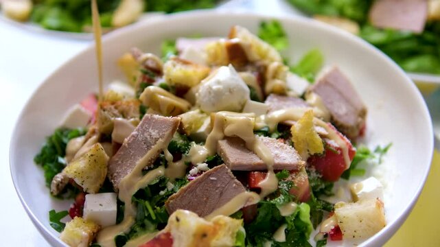 Caesar salad dressing Caesar salad is prepared in the restaurant kitchen. Caesar salad with grilled beaf meat, parmesan cheese