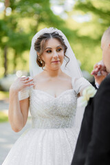 A bride and groom are standing in front of a tree. The bride is wearing a white dress and a tiara....