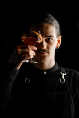 Young man with black hair and mustache hold in his hands a glass with rum or cognac