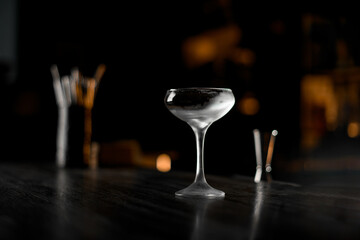 Stylish ice glass stand on a wooden bar counter on a blurred background