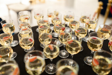 A table full of wine glasses with fruit in them. The glasses are all different sizes and are arranged in a neat row