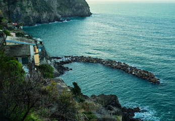 View from the top of a striking cliff overlooking the azure sea with boulders and rocks, Cinque Terre in Liguria