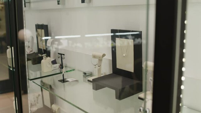 No people shot of elegant pearl pieces of jewellery displayed in highlighted glass showcase in premium fashionable boutique