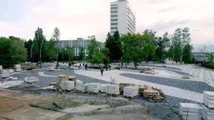 Park littered with paving stones and construction debris at daytime. Employees working on park renewal in city center at day timelapse