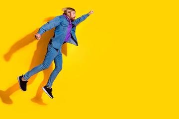 Full size photo of nice young man jump fly empty space wear denim jacket isolated on yellow color background