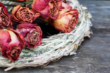 Red dried roses on a hay wreath.