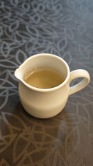 Freshly Poured Sugar Syrup in a Simple White Porcelain Pitcher on a Patterned Tablecloth