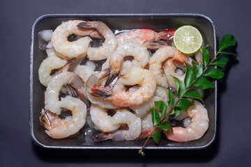 Fresh shrimps prawns seafood lemon lime with herbs and spice, Shrimp peeled on wooden board dark background dining table food, top view. copy space.