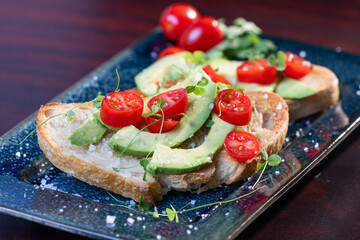 A slice of toasted sour dough bread with avocado and tomato on top