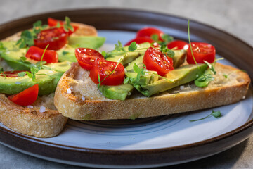 A slice of toasted sour dough bread with avocado and tomato on top