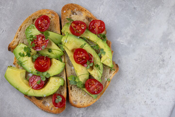 A slice of toasted sour dough bread with avocado and tomato on top