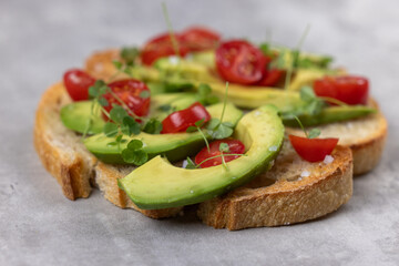 A slice of toasted sour dough bread with avocado and tomato on top
