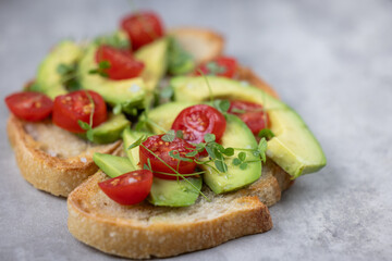 A slice of toasted sour dough bread with avocado and tomato on top