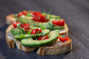 A slice of toasted sour dough bread with avocado and tomato on top