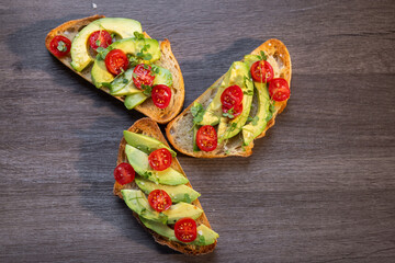 A slice of toasted sour dough bread with avocado and tomato on top