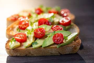 A slice of toasted sour dough bread with avocado and tomato on top