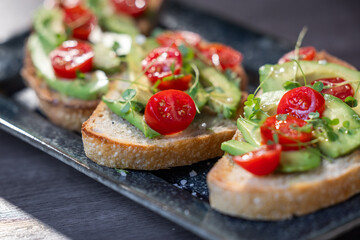 A slice of toasted sour dough bread with avocado and tomato on top