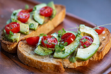 A slice of toasted sour dough bread with avocado and tomato on top