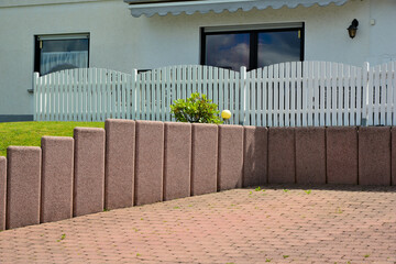 Senkrecht eingebaute Betonelemente als Mauer und Strukturelement vor  einem Wohnhaus