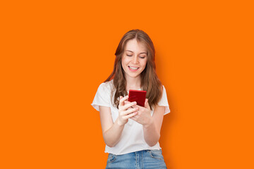 Smiling woman using smartphone on orange background