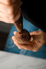 Bag of cream in hands of pastry chef in blue jeans who makes macarons