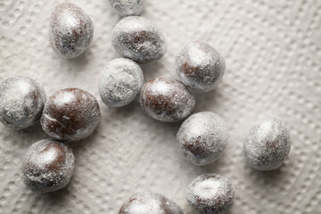 Chocolate balls in silver sprinkles a on a white relief surface for decoration macarons