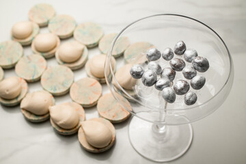 Glass bowl with silver dekor and macaron preparationson a marble table