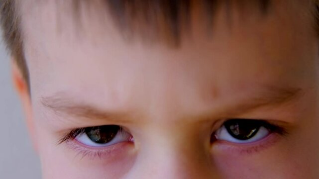 close-up of part of the child's face, boy 8-10 years old Asian-European appearance, human eye looking seriously at the camera, the concept of surveillance, peeping, tracking