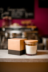 Decorative white candle and a box in neutral tones stand on a bar counter