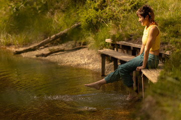 A woman is sitting on a bench by a body of water