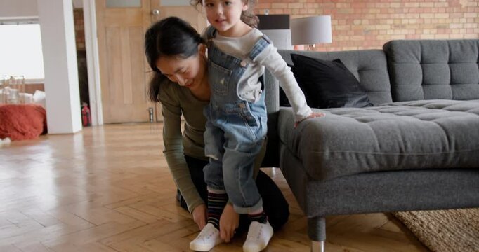 Mother putting on shoes on Daughter at Home