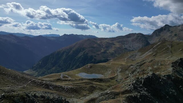 Luftaufnahme des Penser Jochs im Herbst bei Sonnenschein mit ein paar Wolken