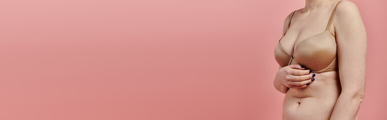 A woman in a bra touches her chest, signifying breast cancer awareness.