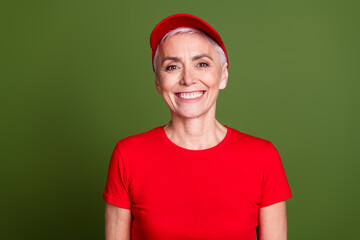 Photo of pretty senior female professional delivery employee cheerful smile wear red uniform workwear isolated on khaki color background