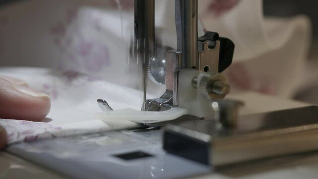 Woman sewing the edges of fabric using a overlock sewing machine, close up