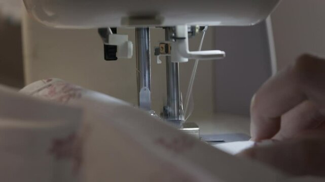 Woman sewing the edges of fabric using a overlock sewing machine, close up