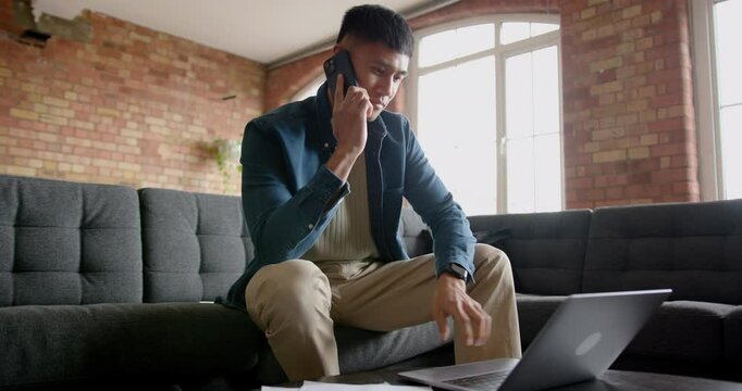 Mid Adult Male Working from Home on a Laptop and Phone sitting on a Sofa