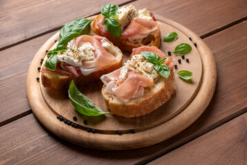 Deliziose bruschette condite con mozzarella di bufala e prosciutto crudo, spuntino italiano 