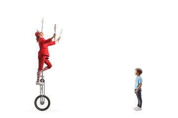 Boy watching an acrobat riding a giraffe unicycle and juggling