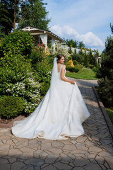 A woman in a white wedding dress is walking down a path in a garden. The scene is serene and peaceful, with the woman looking happy and content