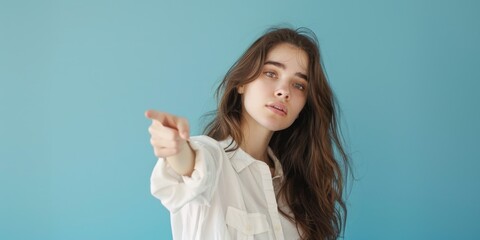 Fototapeta premium A woman in a white shirt points at the camera, focusing attention on her message
