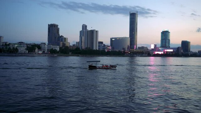 Evening city, boat rides people on the river, promenade
