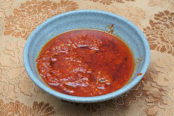 Indonesian red chili sauce in a bowl on a dining table with indoor lighting