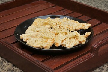 Crispy fried banana. typical Indonesian snack, photographed on a black plate on a table with indoor lighting